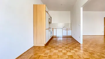Kleine Küchenzeile mit hellen Schränken und Parkettboden, offen zum Wohnbereich.