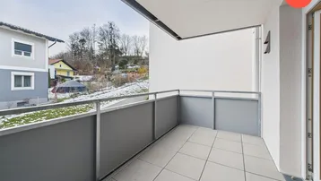 Geräumiger Balkon mit Fliesenboden und Blick auf die verschneite Umgebung und Häuser.