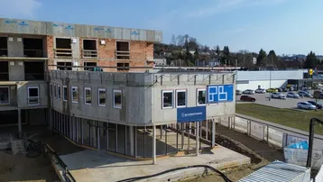 Neubau im Bau, mit sichtbaren Betonstrukturen und Rohbau-Elementen, umgeben von einer Baustelle.