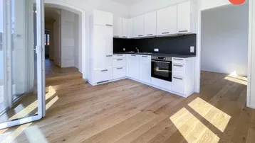 Moderne offene Küche mit weißen Hochglanzschränken, dunkler Arbeitsplatte und hellem Holzfußboden.