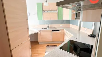 Funktionale Küche mit hellen Holzfronten, grünen Akzenten und Induktionskochfeld.