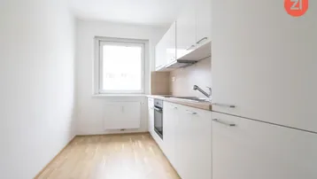 Moderne, helle Küche mit weißen Hochglanzfronten, Holzarbeitsplatte und Fenster.