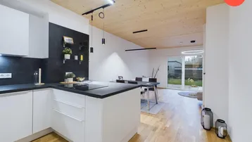Moderne offene Küche mit Kochinsel, Holzboden und Blick in den Garten.