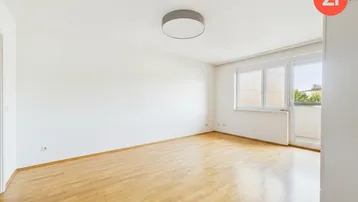 Heller Wohnraum mit Parkettboden, großen Fenstern und direktem Balkonzugang.