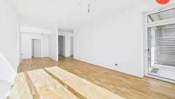 Heller, leerer Wohnbereich mit Holzboden und Zugang zu einem Balkon, ideal für Erstbezug.