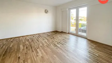Helles Zimmer mit Holzboden und Zugang zu einem französischen Balkon, ideal für ein Wohnzimmer.
