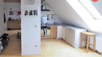 Helle Dachgeschossküche mit Holzboden, Dachfenster und integrierten Geräten in offener Raumgestaltung.