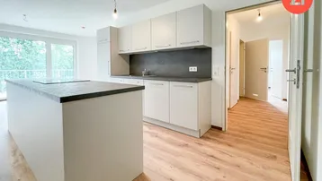 Moderne offene Küche mit Kücheninsel, hellen Schränken und Zugang zum Balkon.