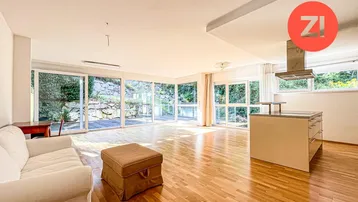 Heller, offener Wohnbereich mit Holzboden, Kücheninsel und großen Fenstern zum Garten.