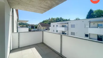 Heller Balkon mit Fliesenboden und Blick auf die umliegende Wohngegend und einen Hügel.