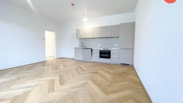 Heller Wohnbereich mit moderner Küchenzeile und elegantem Fischgrätparkettboden.
