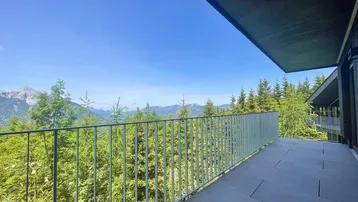 Großer Balkon mit Fliesenboden und Metallgeländer bietet einen atemberaubenden Blick auf die Berge und Wälder.