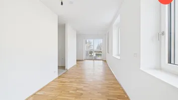 Helles, leeres Zimmer mit Holzboden und Zugang zu einem Balkon, ideal für Wohn- oder Essbereich.