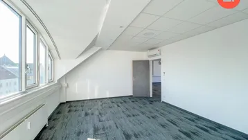 Helles Büro im Dachgeschoss mit Teppichboden, großen Fenstern und Klimaanlage.