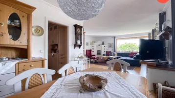 Gemütlicher Essbereich mit Holztisch und Blick in das helle Wohnzimmer mit Kamin und weitem Ausblick.