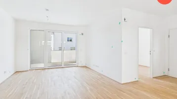 Helles Wohnzimmer mit Parkettboden und Zugang zu einem großen Balkon.