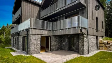 Gebäudeuntergeschoss mit Natursteinfassade, mehreren Balkonen und einer ebenerdigen Terrasse.