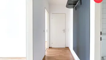 Heller Flur mit Holzfußboden, weiß gestrichenen Wänden und einer modernen Garderobe.