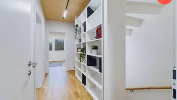 Heller Flur mit Holzdecke, integriertem Bücherregal und Treppenaufgang.