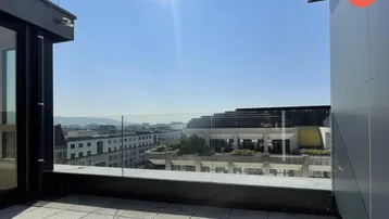 Geräumige Dachterrasse mit Glasgeländer und Panoramablick über die Stadt und die Berge.