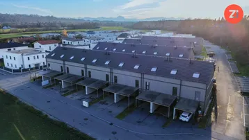 Luftaufnahme einer modernen Reihenhaussiedlung mit Carports und Grünflächen.