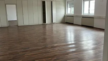 Geräumiges Büro mit Laminatboden, Einbauschränken und großen Fenstern, die viel Tageslicht hereinlassen.