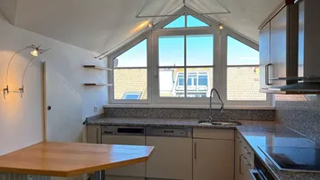 Küche mit Dachschrägen, Granitarbeitsplatten und großem Fenster mit Ausblick.