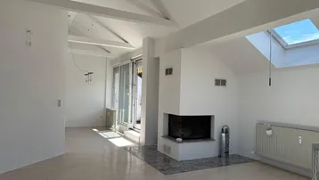 Helles Wohnzimmer mit Kamin, Dachfenster und Holzbalken an der Decke.
