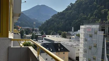 Sonniger Balkon mit Bergblick und Aussicht auf die umliegende Stadt und Natur.