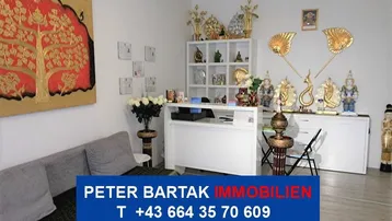 Heller Empfangsbereich mit weißem Tresen, Sofa und vielen goldenen Dekorationselementen an den Wänden.