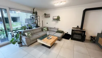 Gemütliches Wohnzimmer mit Kaminofen, großem Sofa und Zugang zum Außenbereich.