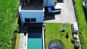 Draufsicht auf das Wohnhaus mit Swimmingpool, großem Garten und sonniger Terrasse.