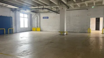 Großer, leerer Industrieraum mit Betonboden, hohen Decken und sichtbaren Installationen, ideal für Lagerung.