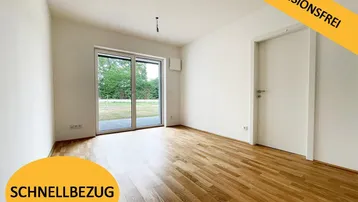 Heller, leerer Raum mit hochwertigem Parkettboden und direktem Zugang zu einem grünen Gartenbereich.