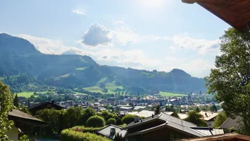 Panoramablick auf die Stadt und die umliegenden Berge von einem sonnigen Aussichtspunkt.