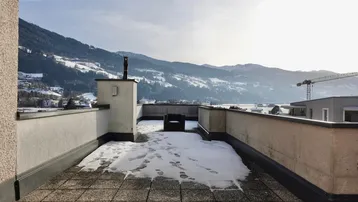 Dachterrasse mit Schnee und weitem Blick auf die umliegende Berglandschaft.