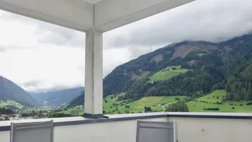Geräumige Terrasse mit Sitzgelegenheiten und einem atemberaubenden Blick auf die umliegende Berglandschaft und das Tal.