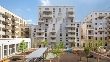 Moderne Wohnanlage mit mehreren Gebäuden, Balkonen und einem zentralen Spielplatz im Innenhof.