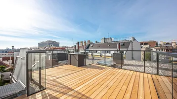 Große Dachterrasse mit Holzbelag und Glasgeländer bietet einen weiten Blick über die Stadt.
