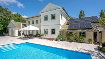 Großzügiger Außenbereich mit Swimmingpool, Sonnenterrasse und Photovoltaikanlage auf dem Dach des Hauses.