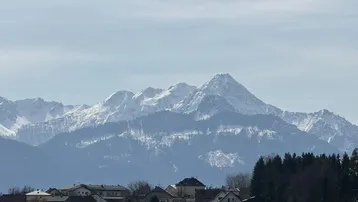 Panoramablick auf schneebedeckte Berge und eine malerische Siedlung im Vordergrund.