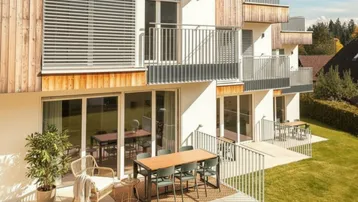 Moderne Wohnanlage mit mehreren Terrassen und Zugang zum grünen Gartenbereich.