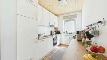 Funktionale Küche mit weißen Schränken, Holztheke und Fenster.