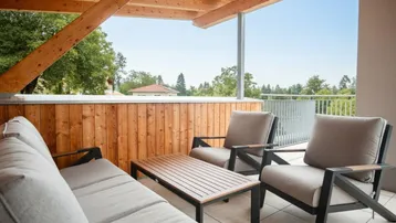 Gemütliche überdachte Terrasse mit Holzbalken und bequemen Outdoor-Möbeln.