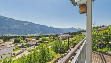 Geräumiger Balkon mit Holzboden und atemberaubendem Blick auf die umliegende Berglandschaft und das Tal.