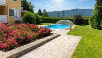 Gepflegter Garten mit Swimmingpool, blühenden Rosenbeeten und einem schönen Bergblick an einem sonnigen Tag.