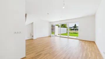 Helles Wohnzimmer mit Holzboden und großen Fenstern, die Zugang zum Garten bieten.