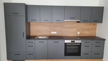 Moderne Einbauküche in Anthrazit mit Holzrückwand und integrierten Elektrogeräten.