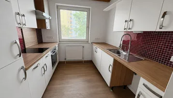 Helle Küche mit weißen Schränken, Holzoptik-Arbeitsplatten und roten Fliesen als Spritzschutz.