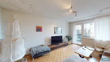 Helles Wohnzimmer mit traditionellem Kachelofen, Parkettboden und Zugang zum Balkon.